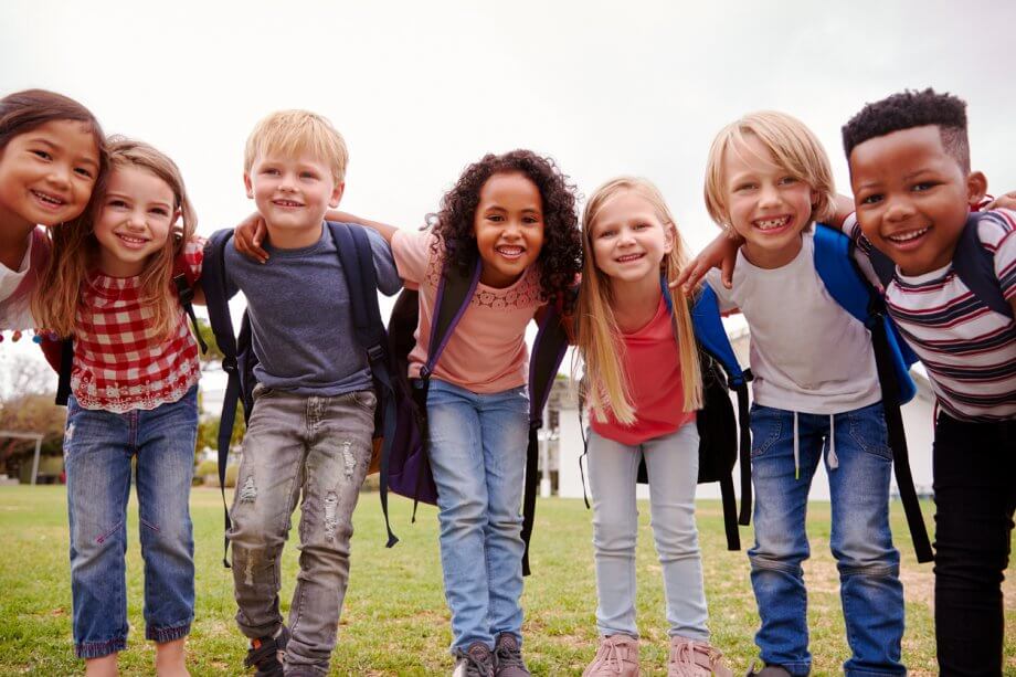 A group of happy children huddled together on a field, surrounded by nature.