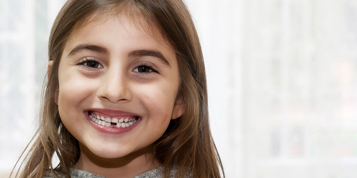 Smiling girl with lower front tooth missing