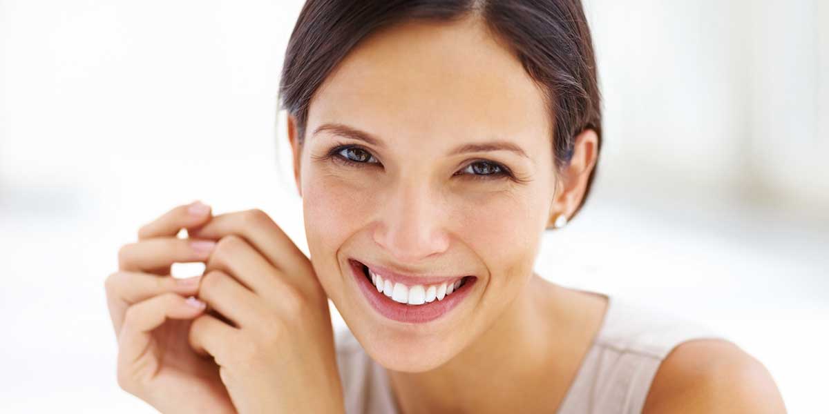 Smiling woman with hands near face