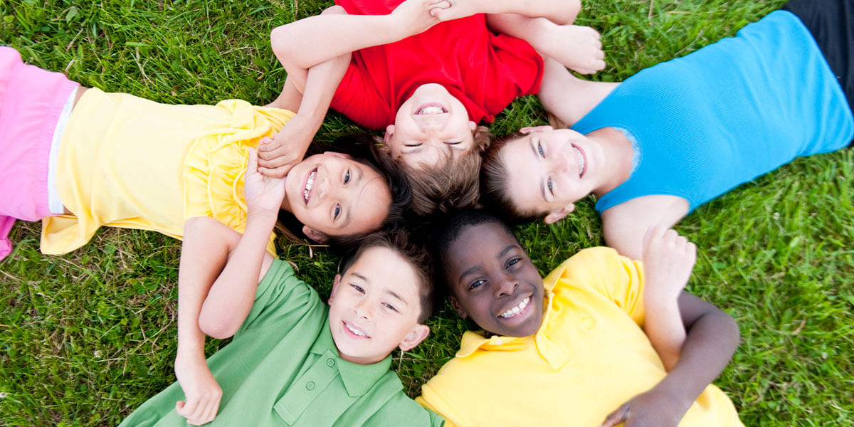 Kids in group locking arms while laying on the ground