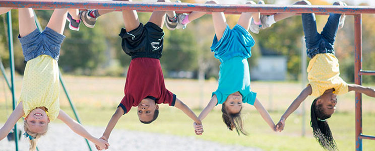 Kids holding hands while hanging upside down from the monkey bars