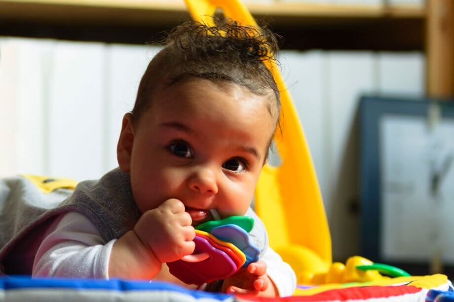 teething baby chews on toy